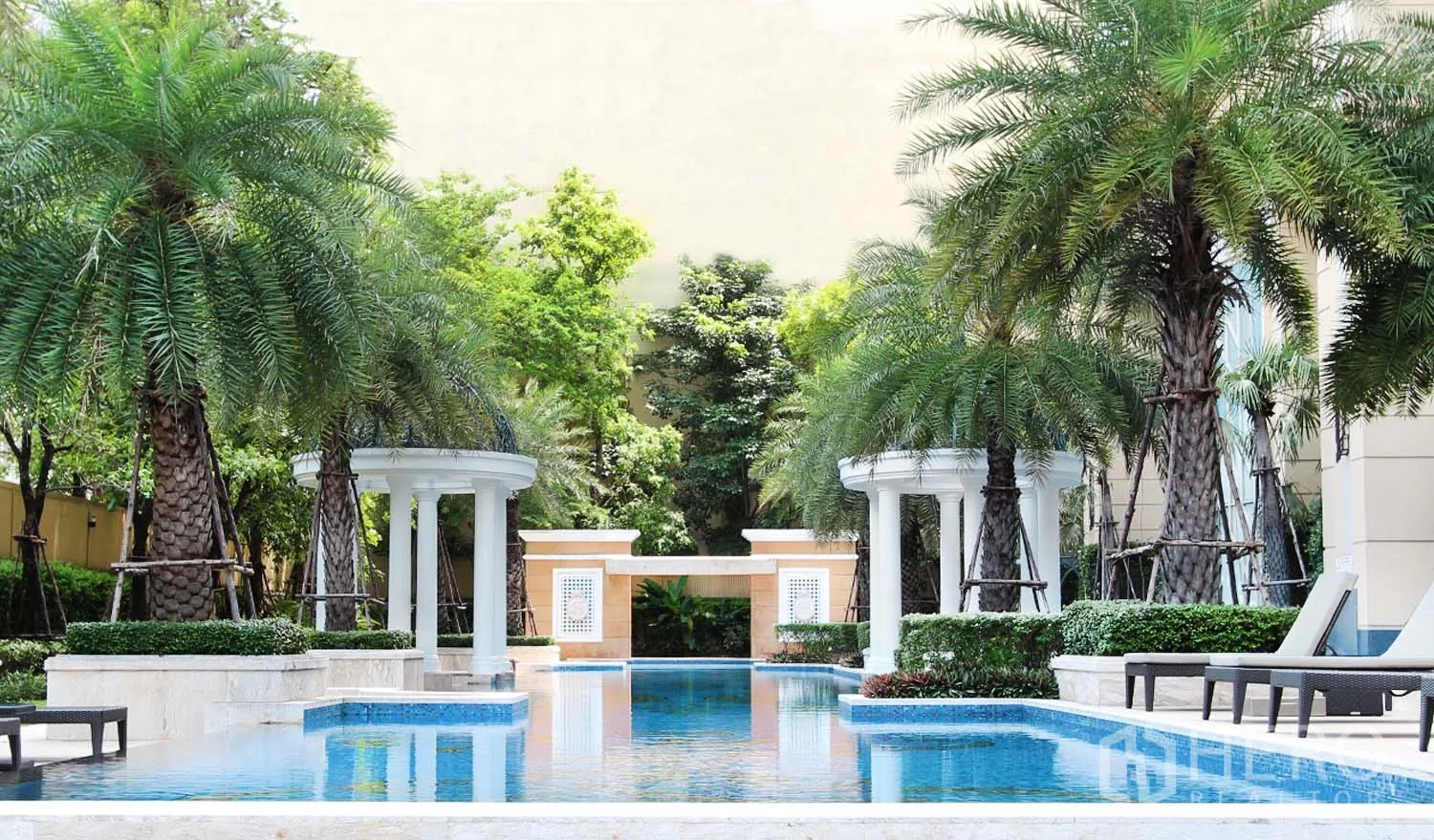 Condominium for rent in Watthana, Bangkok - Resort-style swimming pool with palm trees, loungers and landscaped garden.
