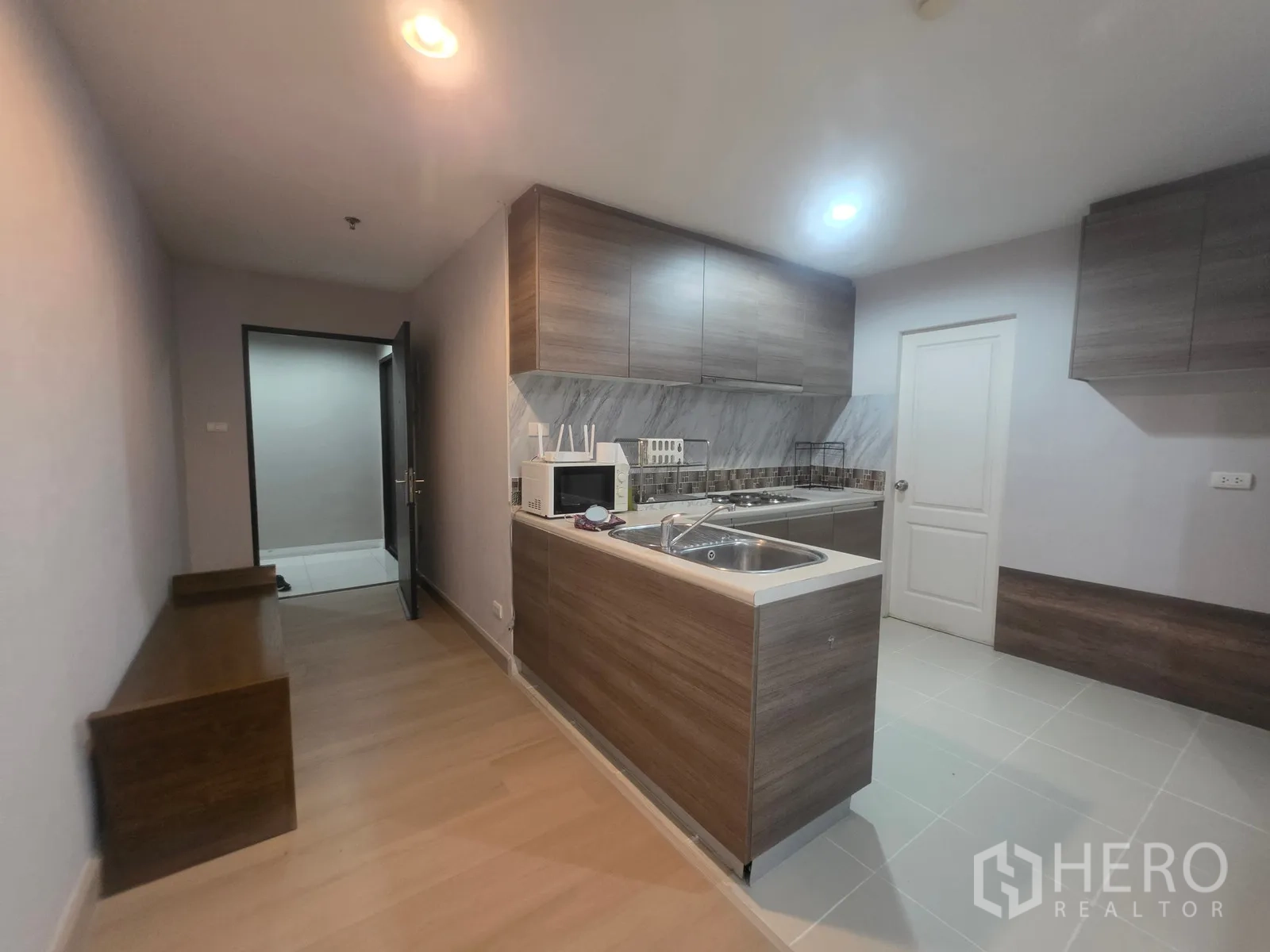 Condominium for rent in Huai Khwang, Bangkok - Kitchen corridor with sink island, microwave, and ample cabinets.