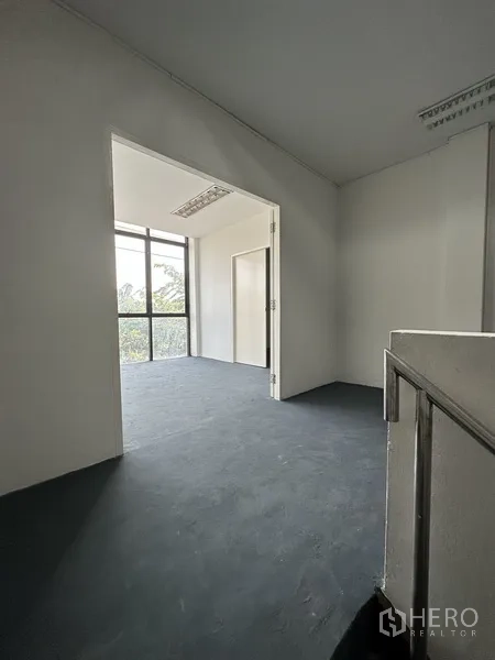 Shophouse for rent in Bang Na, Bangkok - Stair landing opening to a bright room with large windows for natural light.