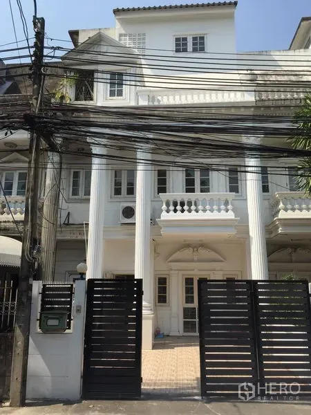 Townhouse for rent in Chatuchak, Bangkok - White multi-storey townhouse in Chatuchak with classical columns, balconies and a black sliding gate.