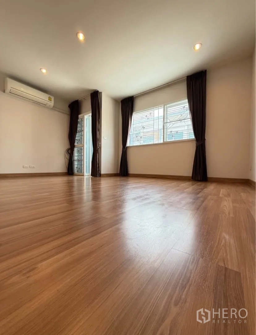 Townhouse for rent in Suan Luang, Bangkok - Large bedroom with wood floors, corner windows and air conditioner.
