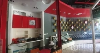 零售空间 出租在Khlong Toei, Bangkok - 前台配红色柜体与现代天花，旁侧为顾客座位区。