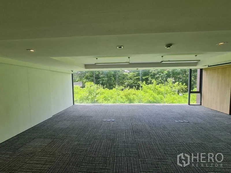 สำนักงาน ให้เช่าในWatthana, Bangkok - พื้นสำนักงานกว้าง กระจกพาโนรามิคมองเห็นต้นไม้ พื้นพรมเข้ม ช่องปลั๊กไฟใต้พื้น และไฟ LED ฝ้าเพดาน.