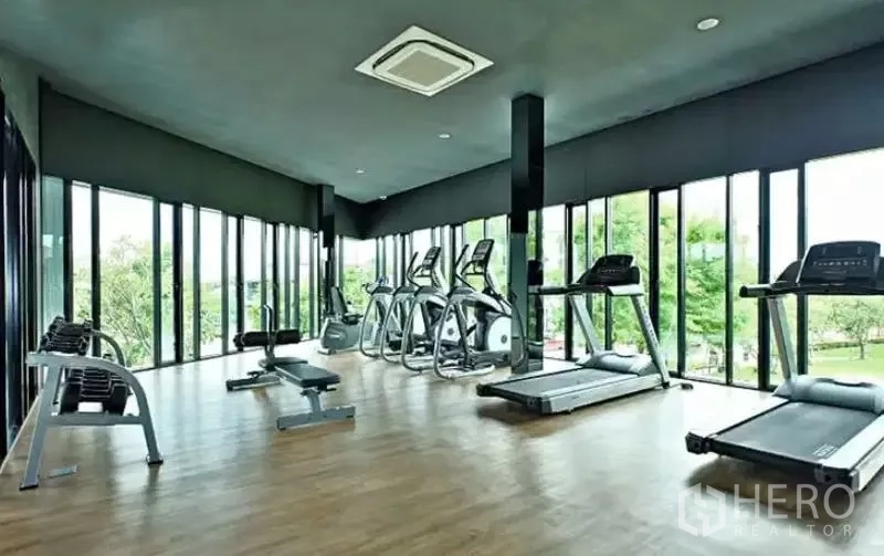 Detached House for sale in Bang Kapi, Bangkok - Fitness room with treadmills, ellipticals and floor-to-ceiling windows.