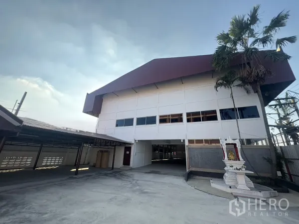 货栈 出租在Bang Phli, Samut Prakan - 邦普里大型白色仓库外立面，红褐色屋顶，入口车道与神龛。