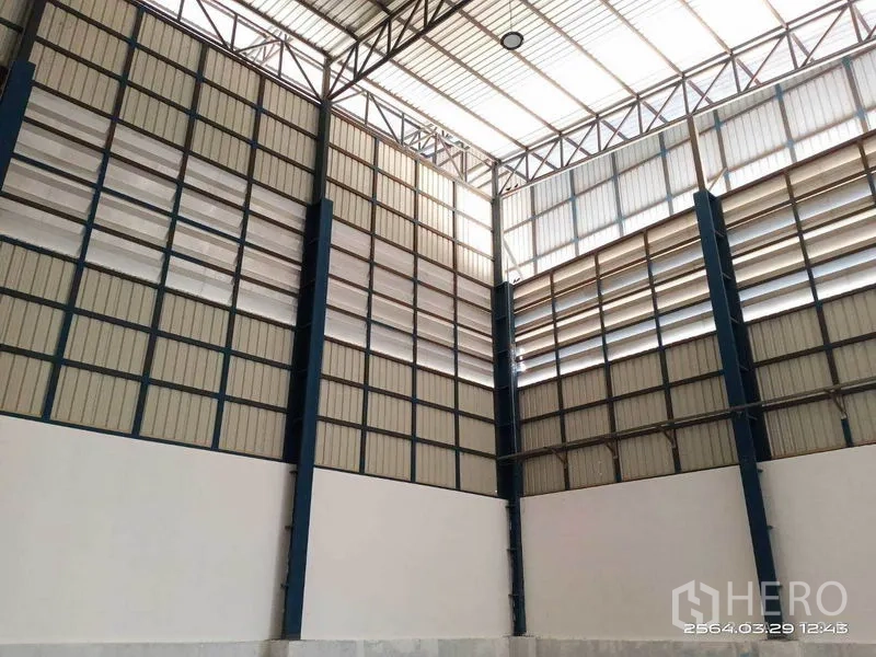 Warehouse for rent in Bang Bo, Samut Prakan - High-clear warehouse interior with steel trusses and louvered wall panels allowing natural light.