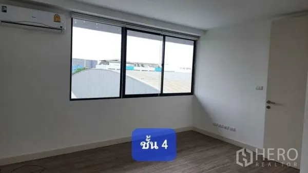 Townhouse for rent in Bueng Kum, Bangkok - Bright upper-floor bedroom with large windows, wood-look flooring and wall-mounted air conditioner.