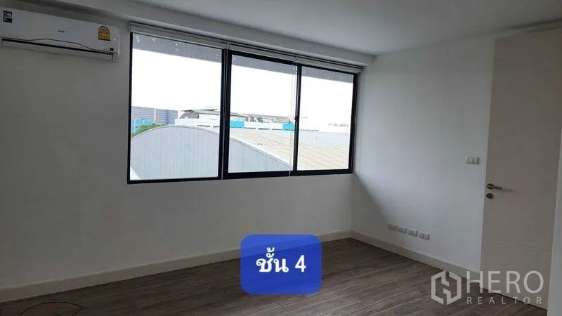Townhouse for rent in Bueng Kum, Bangkok - Bright upper-floor bedroom with large windows, wood-look flooring and wall-mounted air conditioner.