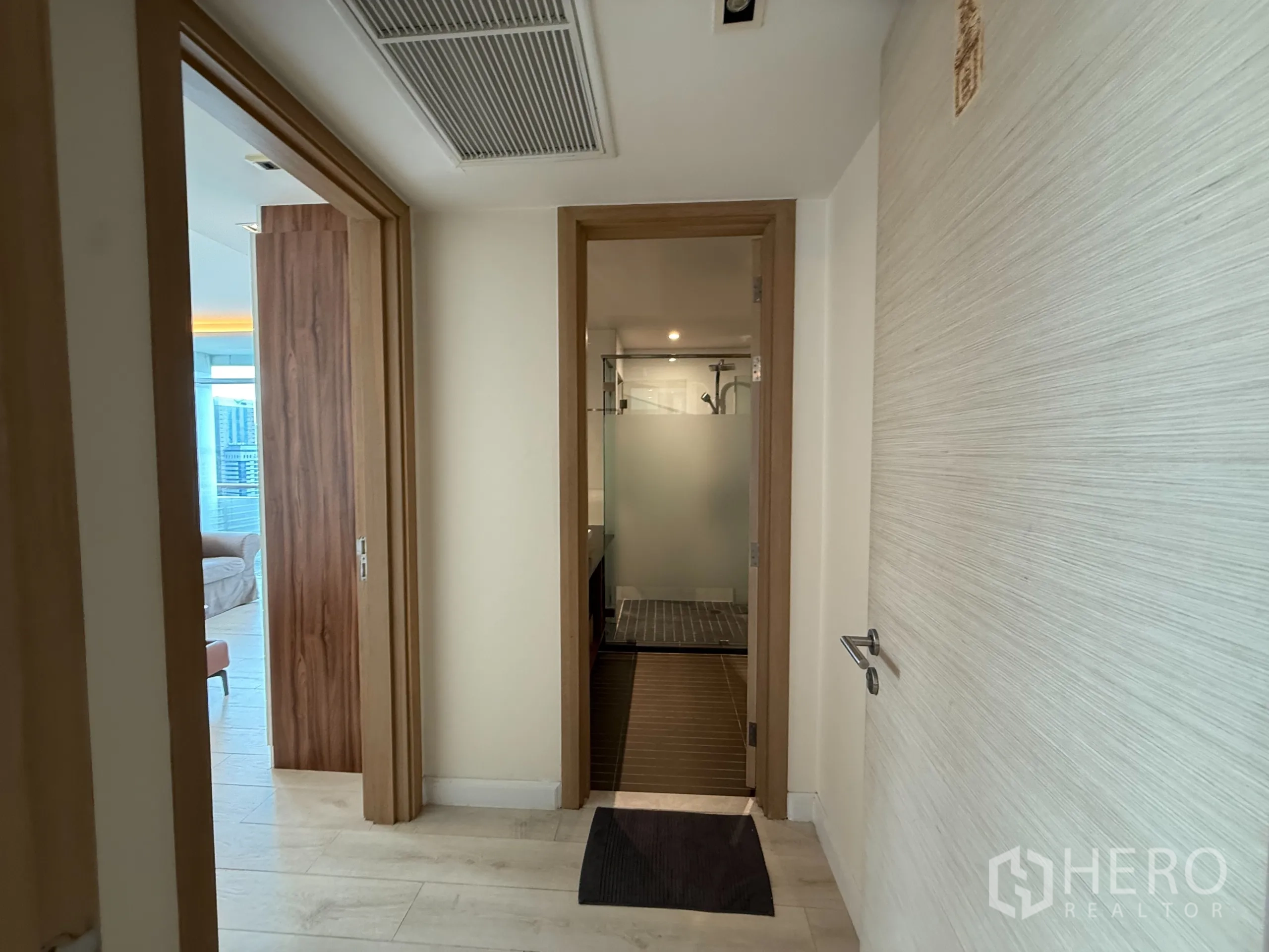 Condominium for rent in Phaya Thai, Bangkok - Entrance hall toward bathroom with frosted‑glass shower and bedroom beyond.