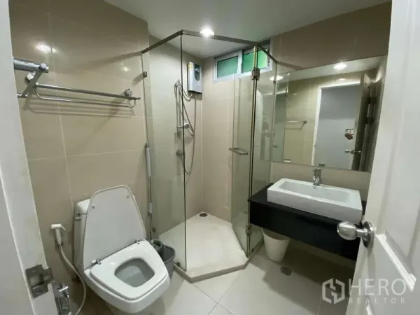 คอนโด for ในHuai Khwang, Bangkok - ห้องน้ำสมัยใหม่ มีตู้กระจกอาบน้ำ อ่างล้างหน้า และโถสุขภัณฑ์ ผนังกระเบื้องสีเบจ
