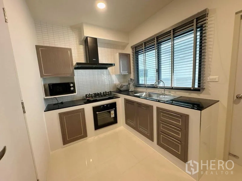 Detached House for rent or sale - Modern L-shaped kitchen with gas hob, oven, hood, microwave and long window with blinds.