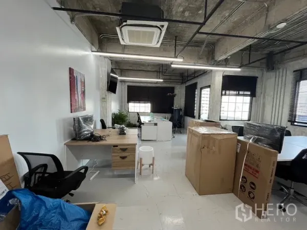 Office Space for rent in Khlong Toei, Bangkok - Open-plan workspace with exposed ducting, cassette AC, desks and moving boxes under linear LED lighting.