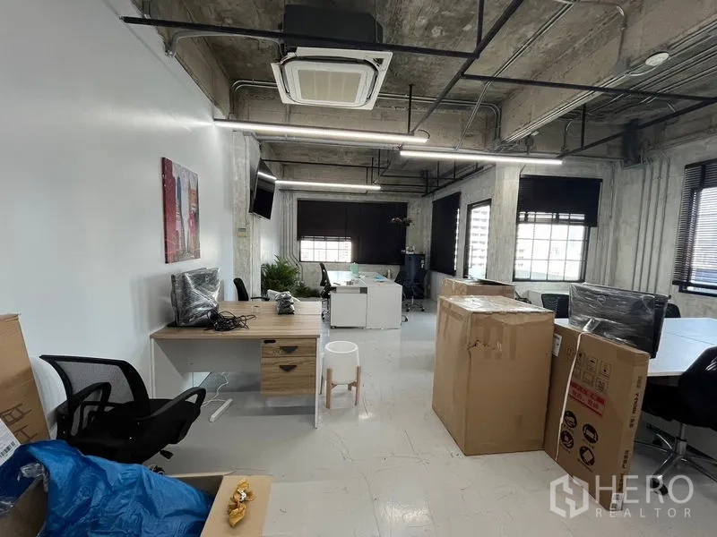 Office Space for rent in Khlong Toei, Bangkok - Open-plan workspace with exposed ducting, cassette AC, desks and moving boxes under linear LED lighting.