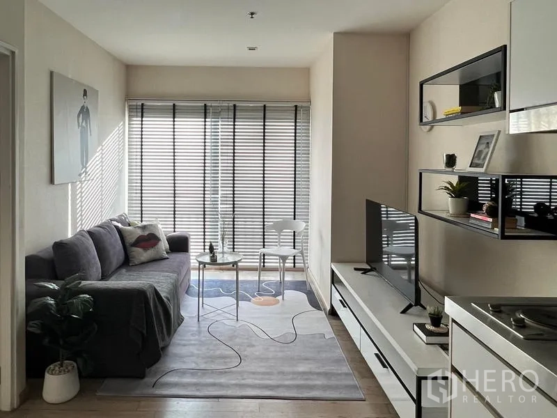 Condominium for rent in Khlong Toei, Bangkok - Long view across the living space toward the window, sofa and TV unit.