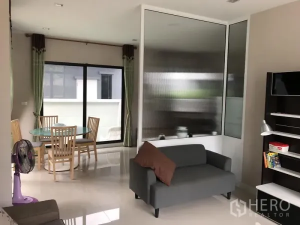 Detached House for rent in Saphan Sung, Bangkok - Open-plan lounge and dining area with glass partition and sliding doors to a terrace.