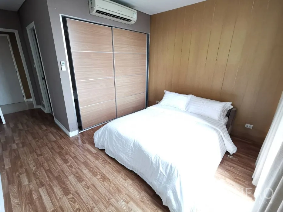 公寓 出租在Watthana, Bangkok - 次卧配双人床，木饰面墙，推拉衣柜与木地板。