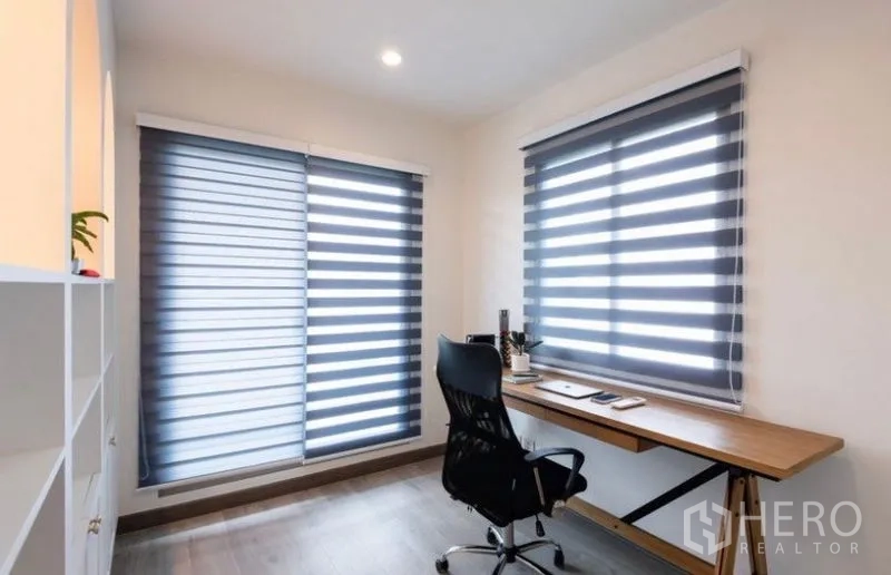 Detached House for rent or sale in Saphan Sung, Bangkok - Corner home office with zebra blinds, wood desk, and swivel chair.