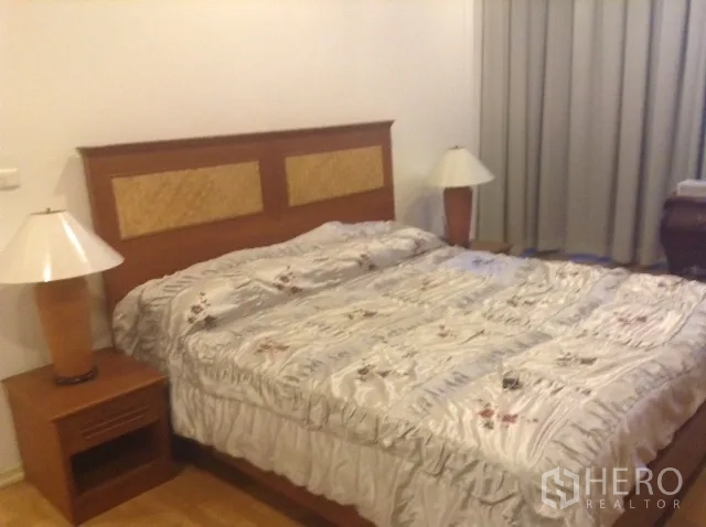 Condominium for rent or sale in Din Daeng, Bangkok - Master bedroom featuring a king-size bed, matching bedside tables with lamps, and full-length curtains.