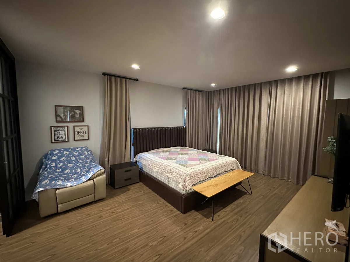 Detached House for rent or sale in Lam Luk Ka, Pathum Thani - Large master bedroom with king bed, full‑height curtains and seating corner.