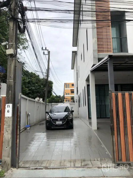 Townhouse for sale in Phra Khanong, Bangkok - Long tiled driveway beside the townhouse providing multiple car parking behind a wooden gate.