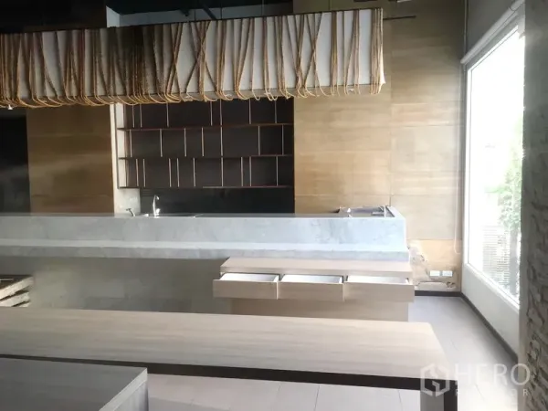 Retail Space for rent in Khlong Toei, Bangkok - Modern retail interior with marble service counter, wood shelving, and a floor-to-ceiling window.