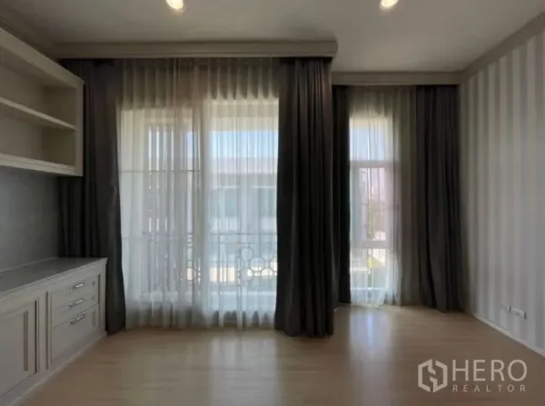 Townhouse for sale - Bright bedroom with floor-to-ceiling windows, sheer curtains, and built-in cabinet on wood flooring.
