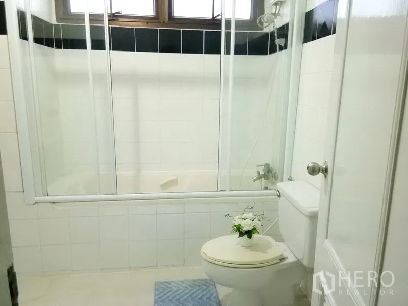 Condominium for rent in Watthana, Bangkok - Bathroom with shower-over-bathtub, glass enclosure and white tiles.