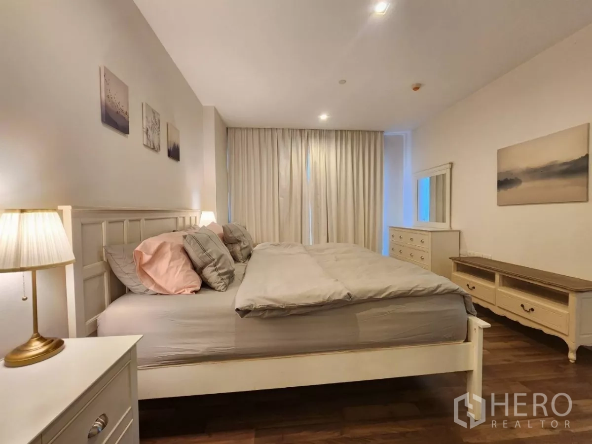 Condominium for rent in Phra Khanong, Bangkok - Master bedroom side view with dresser, mirror, and curtains.