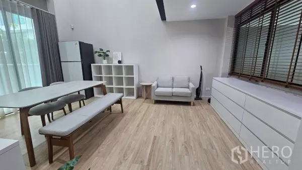 Townhouse for rent in Saphan Sung, Bangkok - Open-plan living and dining space with large windows, bench dining set and light wood floors.