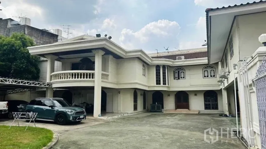 Detached House for sale in Huai Khwang, Bangkok - Grand two-storey detached house with columned balcony, arched windows, and a wide forecourt for multiple cars in Huai Khwang, Bangkok.