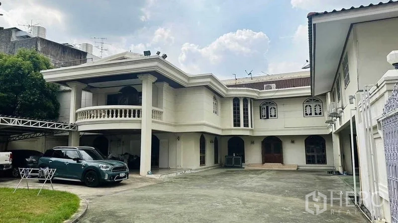Detached House for sale in Huai Khwang, Bangkok - Grand two-storey detached house with columned balcony, arched windows, and a wide forecourt for multiple cars in Huai Khwang, Bangkok.