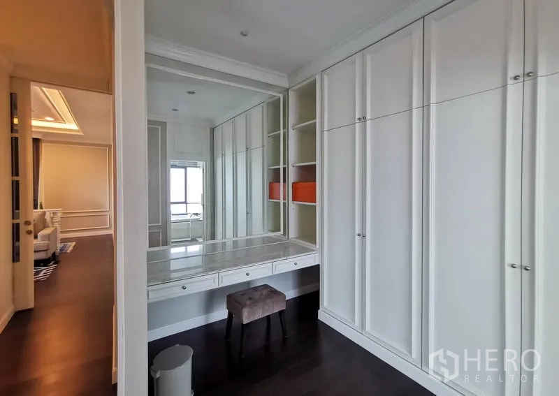 Detached House for rent or sale in Bang Kapi, Bangkok - Walk-in closet with full-height cabinetry, large mirror, and dressing table with stool.