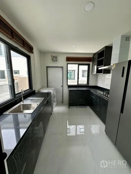 Detached House for rent in Bang Phli, Samut Prakan - Galley kitchen with dual counters, stainless sink, and large windows for natural light.