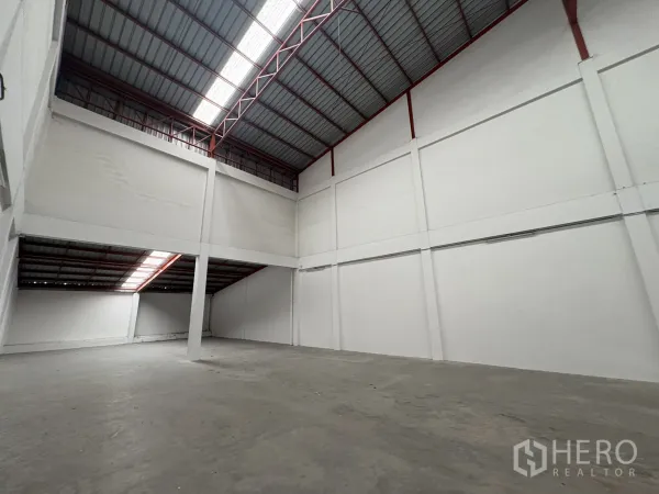 Factory for rent in Phra Samut Chedi, Samut Prakan - Open factory space with partial mezzanine and central column under ventilated roof.
