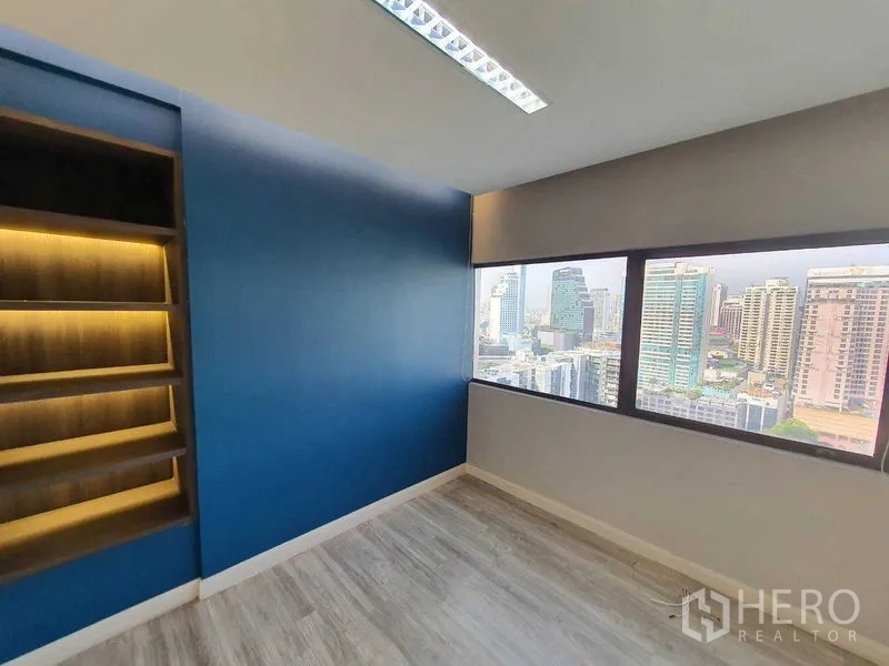 Office Space for rent in Watthana, Bangkok - Small meeting room with illuminated shelving and city-view windows.