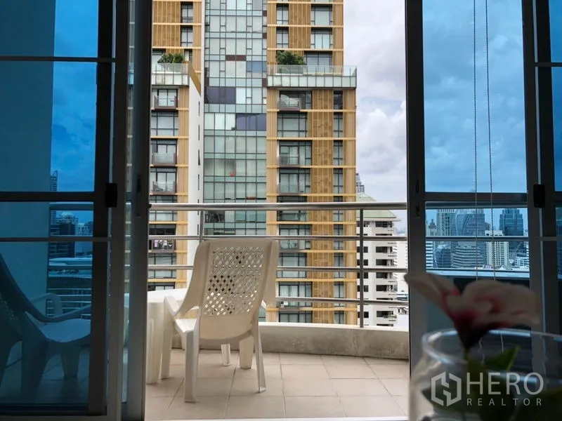 公寓 出租在Pathum Wan, Bangkok - 阳台配椅子，可见邻近高楼与城市天际线。