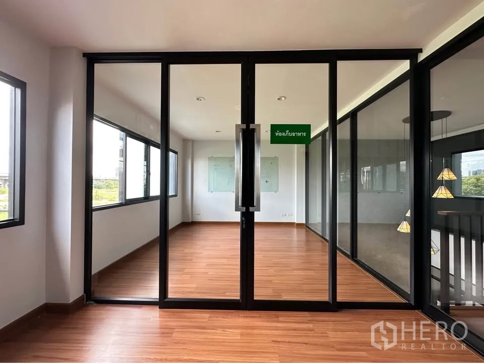 联排别墅 出租在Pak Kret, Nonthaburi - 玻璃隔断多功能房，木地板与环窗采光。