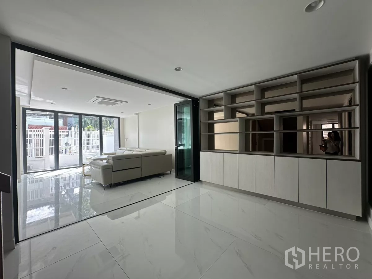 Townhouse for rent in Watthana, Bangkok - Family room with built-in shelving wall opposite a glass partition to the living area.