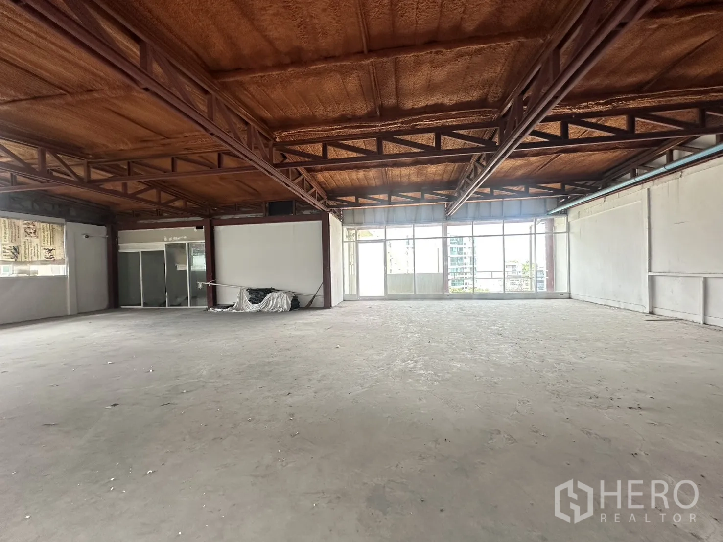 Retail Space for rent in Watthana, Bangkok - Bright corner retail space with large glazing, steel-beam ceiling and unfinished concrete floor.