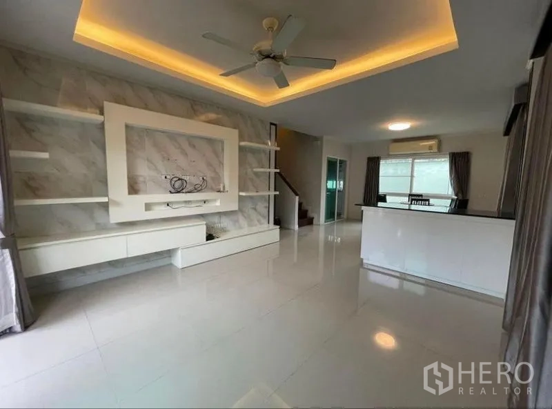 บ้าน ขายในBang Phli, Samut Prakan - ห้องนั่งเล่นโปร่งโล่ง ฝ้าเพดานหลุมไฟซ่อน พัดลมเพดาน และผนังทีวีบิวท์อิน