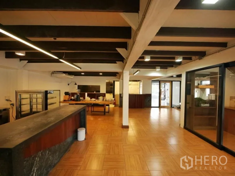 Retail Space for rent in Khlong Toei, Bangkok - Spacious shop interior with a long stone counter, linear ceiling lights, glass partitions and warm flooring.