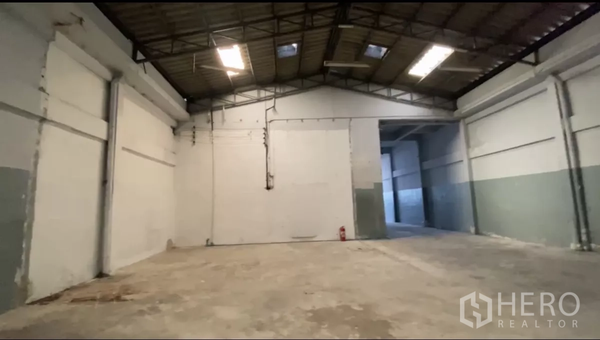 Factory for rent in Bang Phli, Samut Prakan - Separate warehouse chamber linked by a wide opening with fire extinguisher on wall.