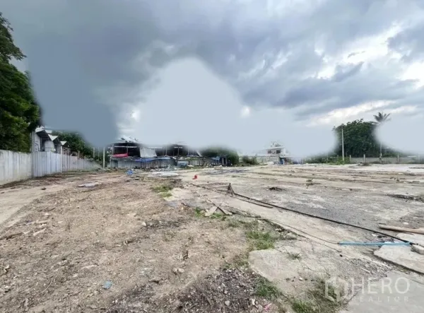 Land for rent in Khlong Toei, Bangkok - Large vacant lot with rough soil and concrete slabs, fenced sides and overcast sky.