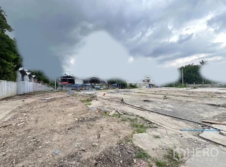 Land for rent in Khlong Toei, Bangkok - Large vacant lot with rough soil and concrete slabs, fenced sides and overcast sky.