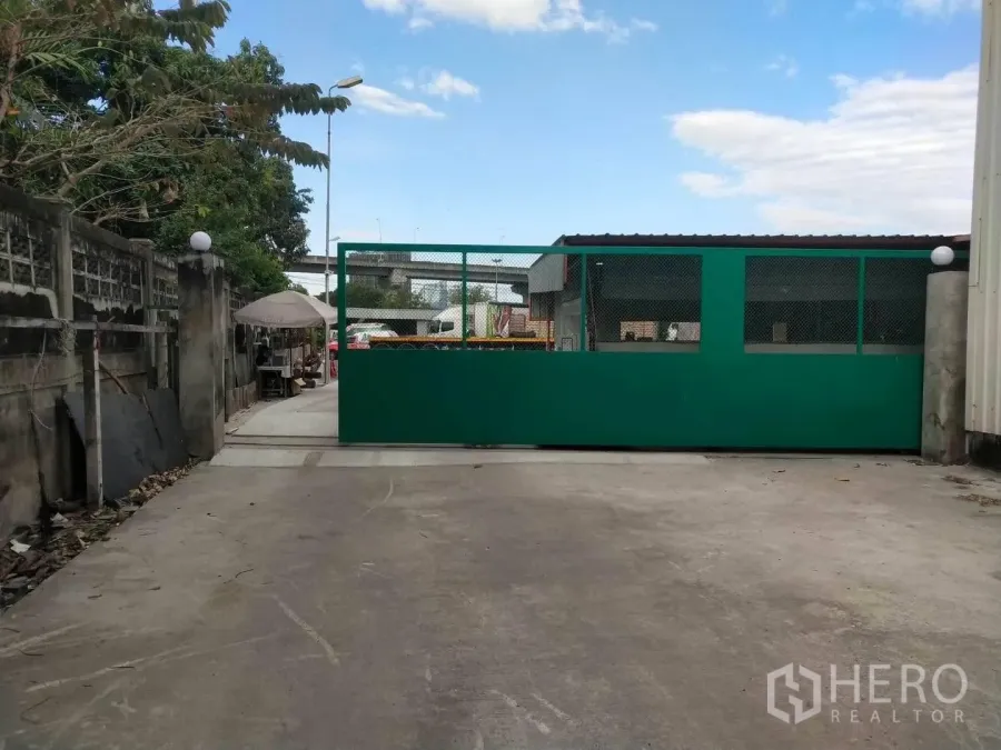 Warehouse for rent in Bang Phli, Samut Prakan - Secure gate and driveway entrance to the warehouse compound.