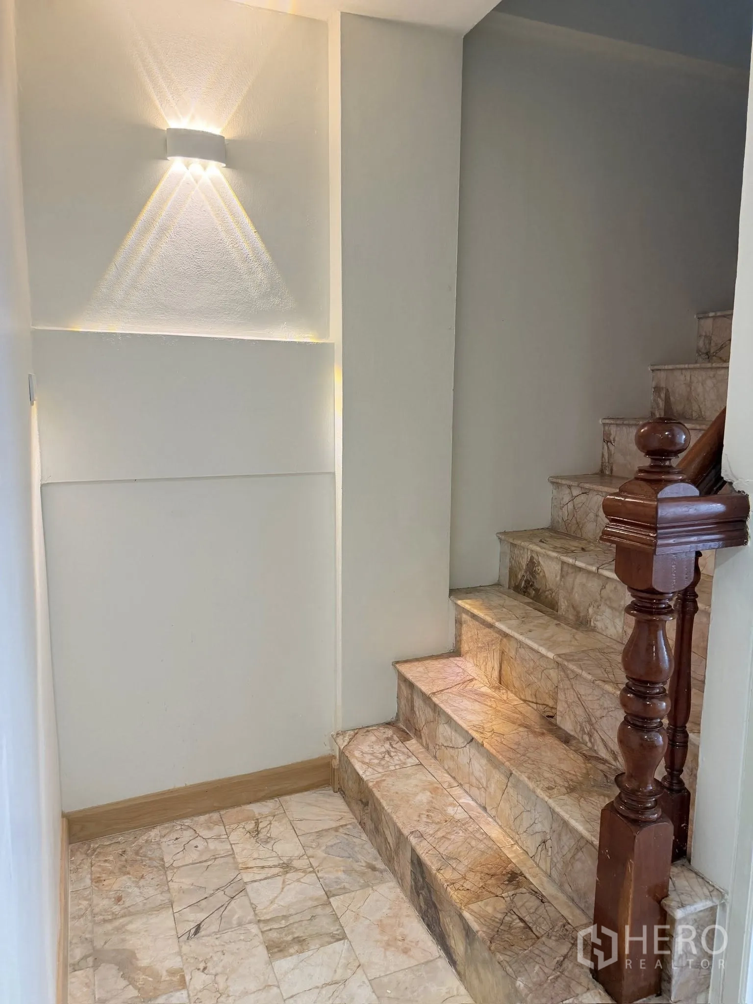 Townhouse for rent or sale in Yan Nawa, Bangkok - Stair landing with wall sconce lighting and marble steps.