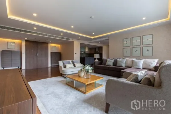 Condominium for sale in Sathon, Bangkok - Open-plan lounge with recessed lighting, sectional sofa and view toward the kitchen.