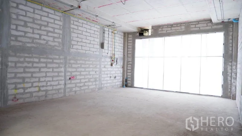 Retail Space for rent in Khlong Toei, Bangkok - Corner view of raw brick walls and a wide glass storefront, ready for tenant fit-out.