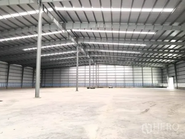 Factory for rent in Bang Phli, Samut Prakan - Expansive empty production hall with tall steel columns and ample natural lighting.