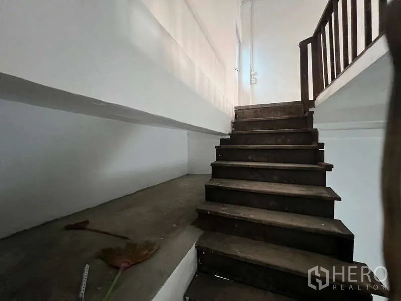Shophouse for rent in Watthana, Bangkok - Close-up of wooden stairs and landing within a white interior.
